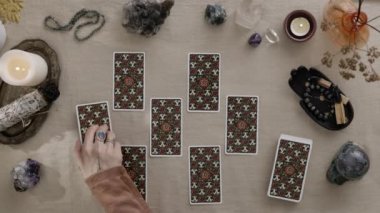 New York, ABD - 1 Mayıs 2021: Top view falcısı elinde yüzüklerle solitaire oynuyor ve mum ışığında tarot kartları okuyor. Kader kehanetleri ve kart konsepti üzerine büyülü bir oturum..