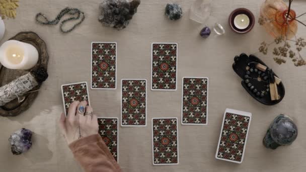New York, USA - 1 May 2021: Top view fortune-teller with rings at her hands playing solitaire and reading tarot cards by candlelight. Predictions of fate and a magical session on the cards concept. — Stock Video