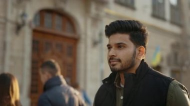 Sıradan giyinen yakışıklı adam şehir caddesinde yürüyor.