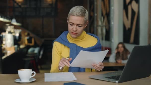 Vrouw typen op laptop en werken met documenten in café — Stockvideo