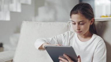 Ellerinde tabletle kanepede oturan rahat kadın çocuk.