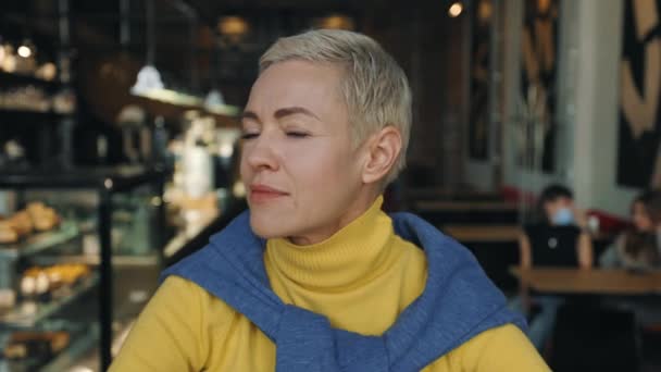 Middle aged woman looking at camera with calm face at cafe — Stock Video