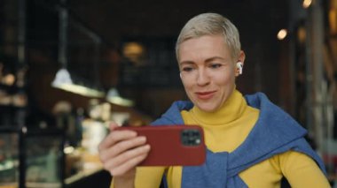 Kafede cep telefonu kullanan orta yaşlı bir kadın.