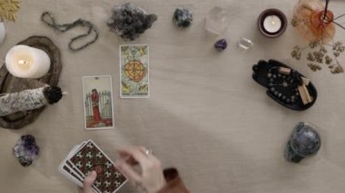 New York, ABD - 1 Mayıs 2021: Parmaklarında dövmeleri olan falcı kadın tarot kartlarıyla geleceği okuyarak resmi masaya koydu. Esrarengiz kavram, falcılık tahminleri.