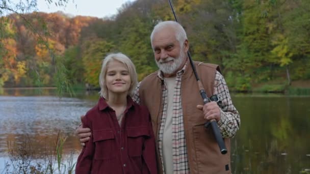 Wnuk i dziadek stojący z wędkami w pobliżu jeziora — Wideo stockowe