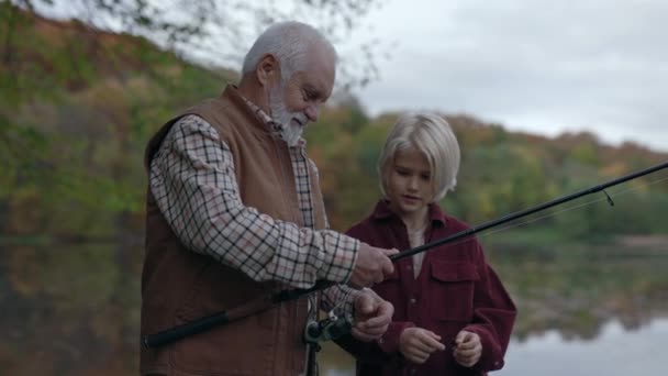 Aged fisherman teaching grandson to cast fishing rod — Stock Video