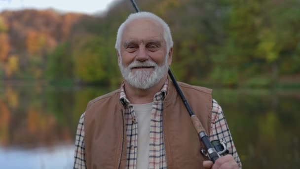 Felice uomo anziano in possesso di canna da pesca mentre in piedi all'aperto — Video Stock