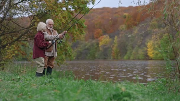 Dědeček a jeho vnuk házejí rybářské pruty do jezera — Stock video