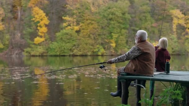 Enkel und Großvater sitzen auf Seebrücke und angeln am See — Stockvideo