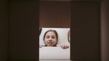 Neşeli çocuk ailesiyle birlikte karton kutuyu açıyor.