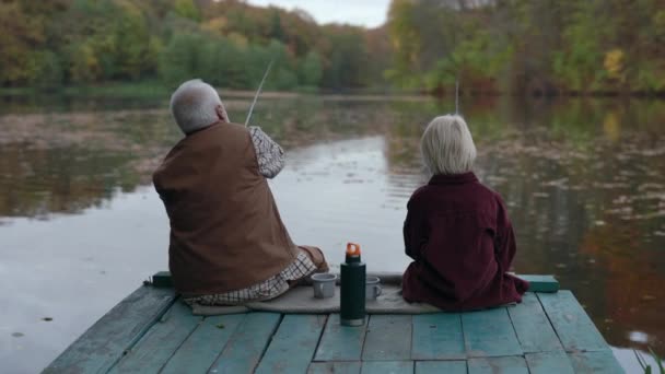 Alter Mann und Teenager Junge sitzen auf Seebrücke und benutzen Angelruten — Stockvideo
