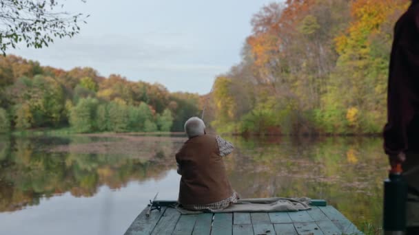 Rückansicht eines alten Mannes, der mit seinem Enkel von der Seebrücke angelt — Stockvideo