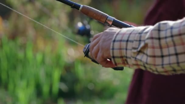Sluiten van oude man met vishengel en draaiende haspel — Stockvideo