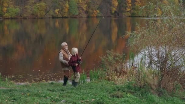 Abuelo ayudando nieto para lanzar caña de pescar en el lago — Vídeo de stock