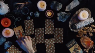 New York, ABD - 1 Mayıs 2021: Kadın kahin elleri karanlık odada otururken geleceği okumak için mistik bir masada tarot kartları oynuyorlar. Geleceği okumak ve tarot kartları oynamak.