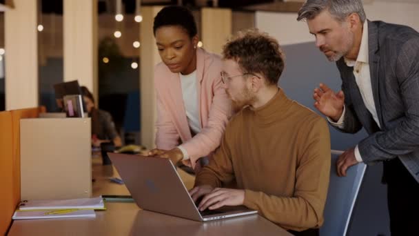 Equipe de negócios criativa multiétnica de três pessoas que discutem o plano de negócios enquanto se sentam à mesa no escritório moderno. Equipe de negócios criativa, grupo multiétnico, espaço de coworking. — Vídeo de Stock