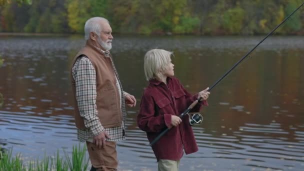 Senior sportfiskare fiske med sitt barnbarn på lokal sjö — Stockvideo