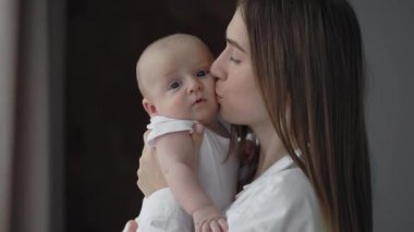 Anne yeni doğan oğlunu kucaklıyor ve öpüyor.