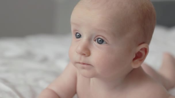 Новорожденный мальчик лежит голым на белой кровати — стоковое видео