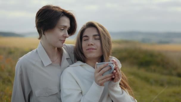 Paar von zwei liebevollen Frauen sitzt mit heißen Getränken in der Natur — Stockvideo