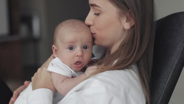 Счастливая мать держит и целует своего новорожденного ребенка — стоковое видео