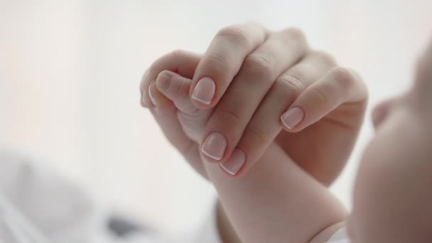 Gentle female hand holding hand of newborn baby — Stock Video