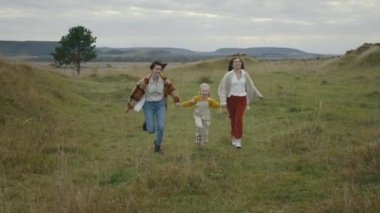 Üç kişilik neşeli Igbt ailesi dışarıda koşuyor ve gülümsüyor.