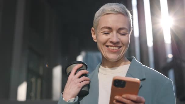 Бизнес-леди с мобильным телефоном и кофе на свежем воздухе — стоковое видео