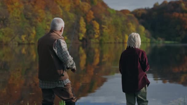 Caucasiano pensionista pesca com neto adolescente no lago local — Vídeo de Stock