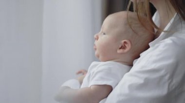 Genç annenin, bebeğinin elini tutarken yakın plan.