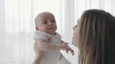 Bakıcı anne yeni doğan oğlunu evde öpüyor.