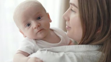 Beyaz bir kadın yeni doğmuş oğlunun elini tutuyor.