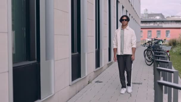 Ung asiatisk blind man med säkerhetpinne för promenader ensam utomhus. Man med glasögon och vardagskläder. Begreppet oberoende. — Stockvideo