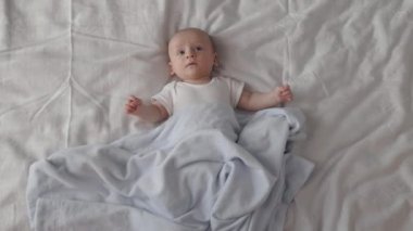 Tatlı erkek bebek yumuşak battaniyenin altında yatıyor.