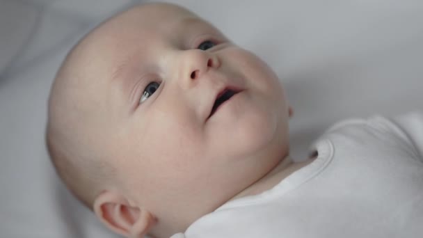 Новорожденный ребенок улыбается и жестикулирует в постели — стоковое видео