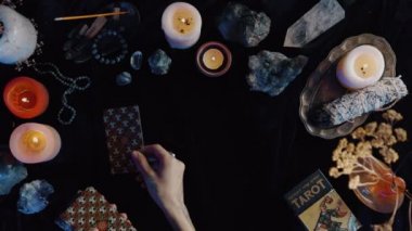 New York, ABD - 1 Mayıs 2021: Falcı kadın elinde bir sürü mumla bir tarot kartında kart düzeniyle tahmin yürüttü. Elinde dövmeleri olan bir kadın masaya taro kartları koyuyor..