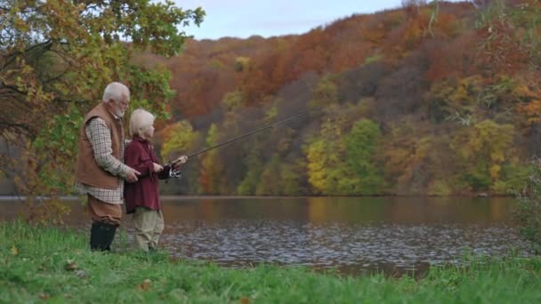 Garçon coulée canne à pêche dans la rivière avec grand-père derrière — Video