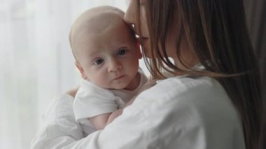 Yeni doğmuş oğlunu kucaklayan ve öpen bir kadın.