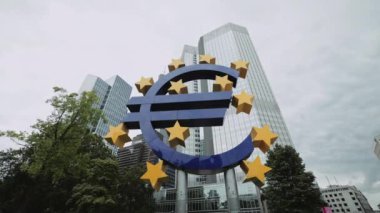FRANKFURT, GERMANY - AĞUSTOS 2021: Frankfurt, Almanya, Avrupa 'da Euro işareti heykeli, 20 Nisan 2018. Arkasında gökdelenler olan mavi-sarı Euro sembol şehir merkezi.