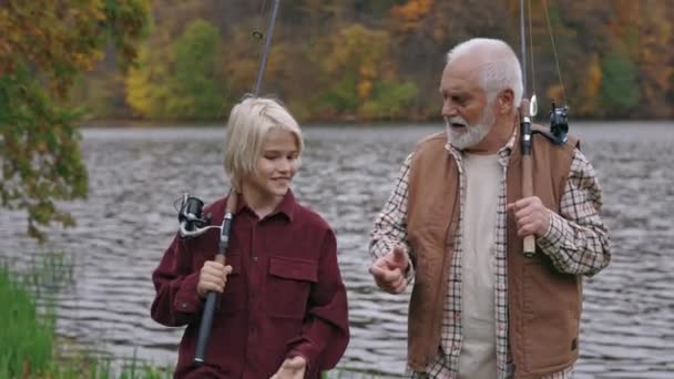 Grand-père avec petit-fils marchant et parlant près du lac — Video