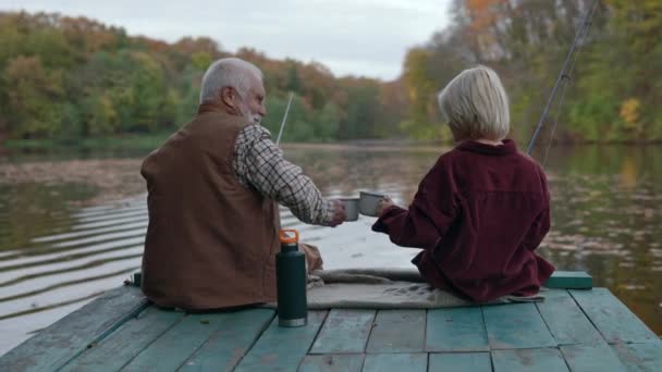 Grootvader en kleinzoon drinken thee en vissen op pier — Stockvideo