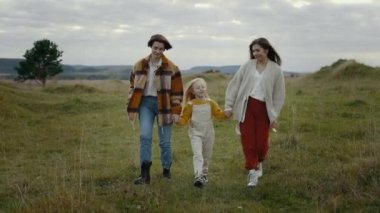 Bir çift lezbiyen yürürken kızıyla el ele tutuşuyor.