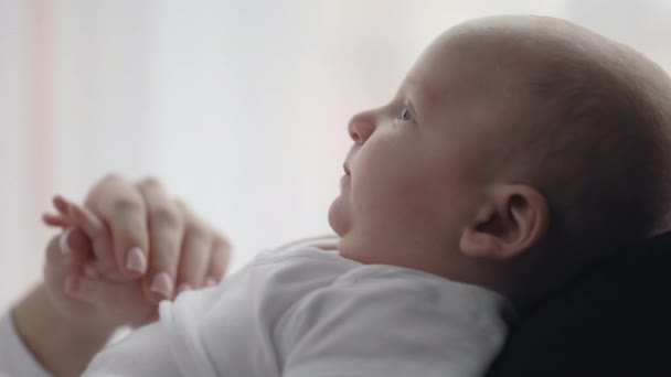 Вид сбоку новорожденного мальчика, лежащего на руках матери — стоковое видео