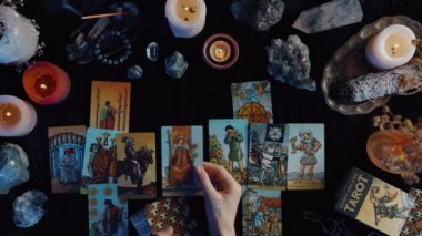 New York, ABD - 1 Mayıs 2021: Falcı, tarot kartlarını masaya koydu ve karanlıkta otururken okumaya hazırlanıyor. Esrarengiz ve kart okuma kavramı.