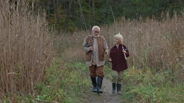 Grandpa and grandson walking with fishing rods and talking — Vídeos de Stock