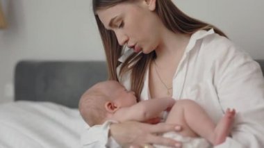 Mother caressing crying newborn son on hands