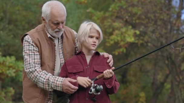 Farfar lär sonson hur man använder fiskespö — Stockvideo