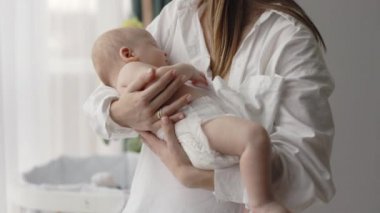 Kafkasyalı genç bir kadın, huzur içinde uyuyan sevimli yeni doğan bir çocukla el ele tutuşuyor. Evde ailece vakit geçireceğiz. Anne ve oğul arasındaki bağ.