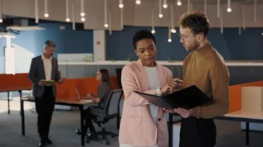 Resmi giysiler içinde iki farklı iş arkadaşı panoya bakıyor ve ofis binasında dikilirken tartışıyorlar. Ortaklar ciddi ifadelerle sohbet ediyorlar
