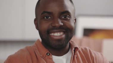 Az önce gelen gülümseyen Afrikalı Amerikalı dairenin sahibinin portresi. Adam yeni dairede dikilip kameraya bakıyor. Yeni ev ve taşınma konsepti